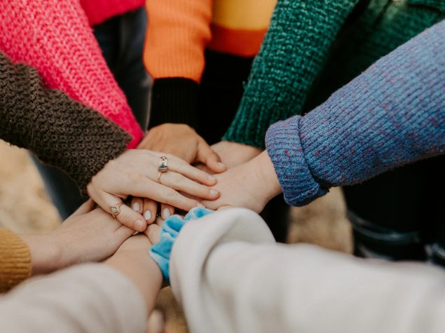 Multiple people with their hands on top of each others